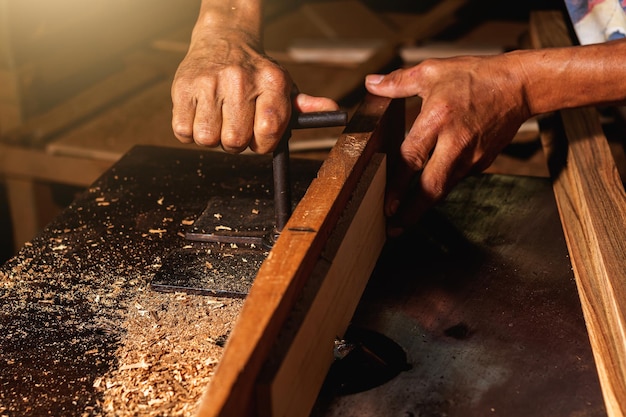 Close-up van een timmerman die een cirkelzaag of een gereedschap gebruikt om houten planken te zagen. Om meubels te maken in huizen en woningen, hotels, kamers van hout.