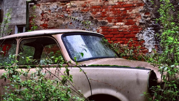 Close-up van een verlaten auto op een bakstenen muur