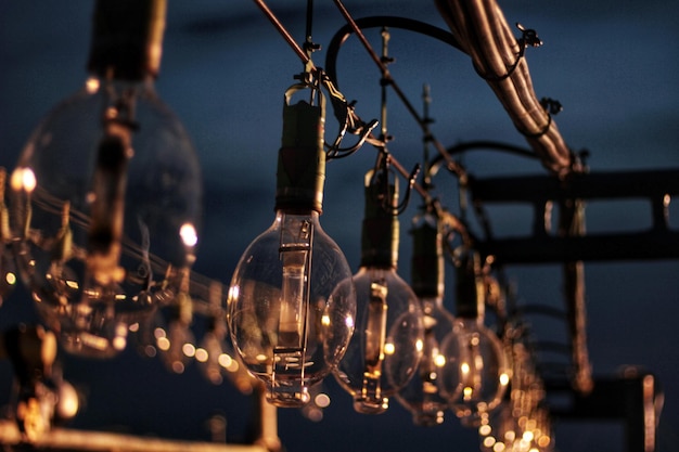 Close-up van een verlichte gloeilamp die's nachts hangt