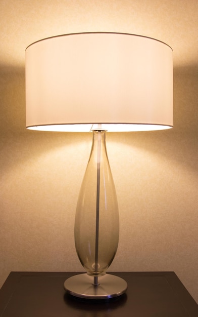 Close-up van een verlichte lamp op tafel tegen de muur thuis