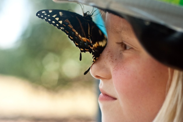 Foto close-up van een vlinder op de neus van een vrouw