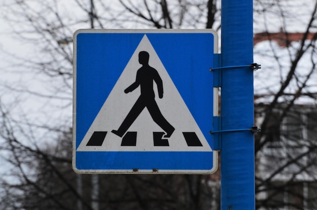 Close-up van een voetgangersovergangsbord tegen een kale boom