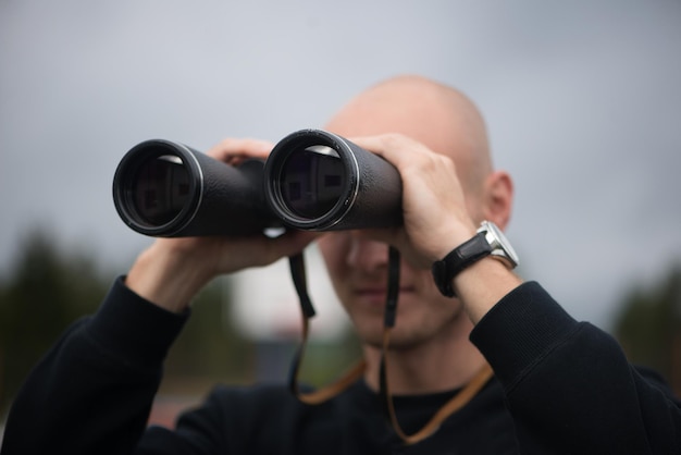 Foto close-up van een volwassen man die door een verrekijker kijkt terwijl hij tegen de hemel staat