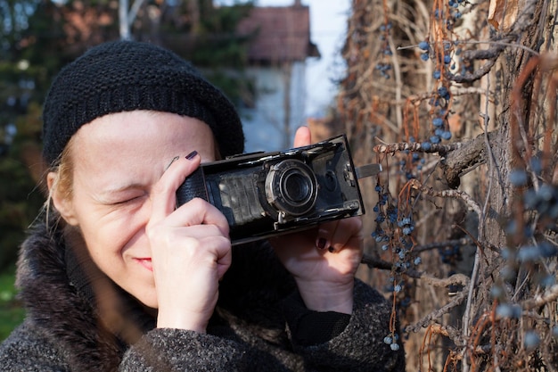 Close-up van een volwassen vrouw die foto's maakt met een vintage camera.