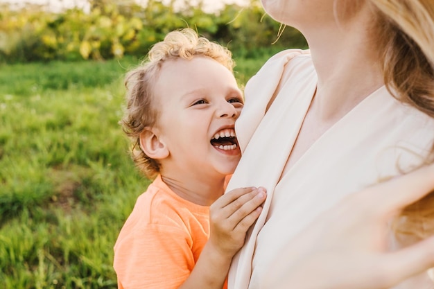 Close-up van een vrolijke jongen die zijn moeder omarmt in het park