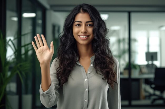 Close-up van een vrouw aan het werk die glimlacht op haar werkplek en een high five geeft aan de camera