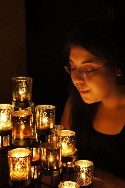 Foto close-up van een vrouw bij brandende kaarsen 's nachts