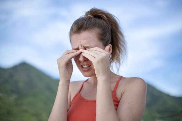 Close-up van een vrouw die aan jeuk krabt en met haar handen in de ogen wrijft in een park met allergie voor het gezichtsvermogen