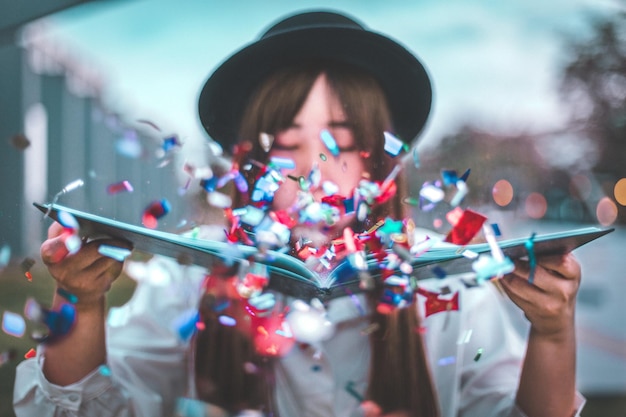 Foto close-up van een vrouw die buiten confetti blaast.