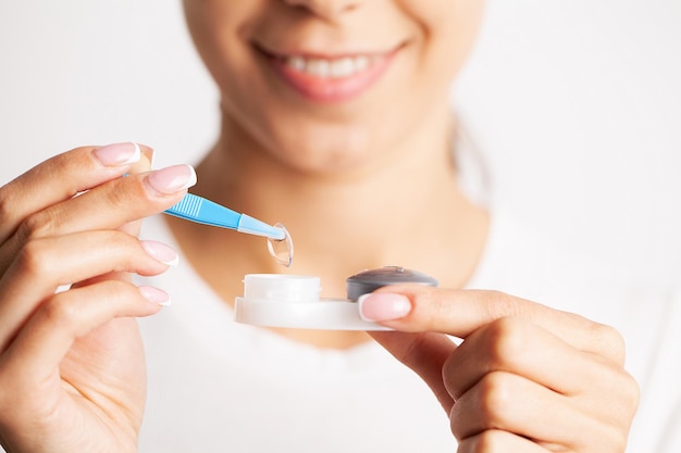 Close-up van een vrouw die contactlenzen uit de container met vloeistof haalt.