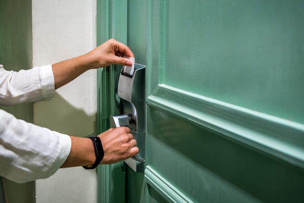 Close-up van een vrouw die de deur opent met een sleutelkaart terwijl ze zijn kamer in een hotel betreedt