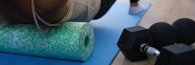 Close-up van een vrouw die een kurkmassagerol berijdt om de spanning in de rugspieren te verlichten