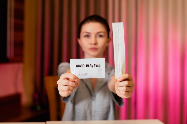 Close-up van een vrouw die een pakket COVID19-sneltest in de hand houdt