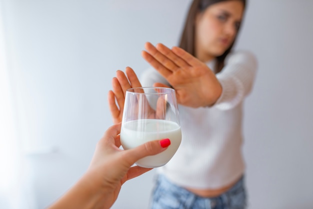 Foto close-up van een vrouw die glas melk thuis verwerpen.