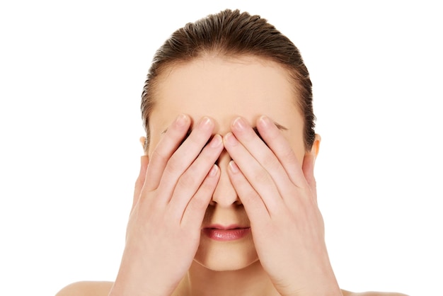 Foto close-up van een vrouw die haar gezicht met haar handen bedekt tegen een witte achtergrond