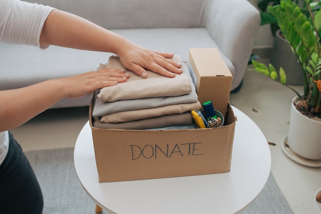 Close-up van een vrouw die kleren in de donatiebox stopt