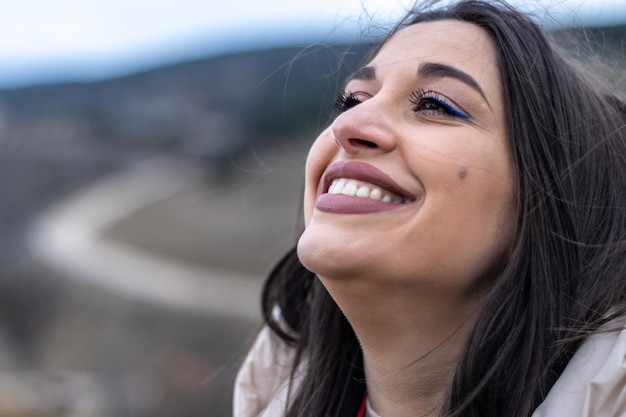 Close up van een vrouw die lacht en kijkt naar de lucht in de natuur