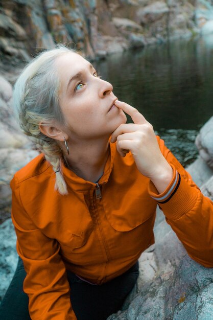 Foto close-up van een vrouw die naar boven kijkt terwijl ze bij het meer zit