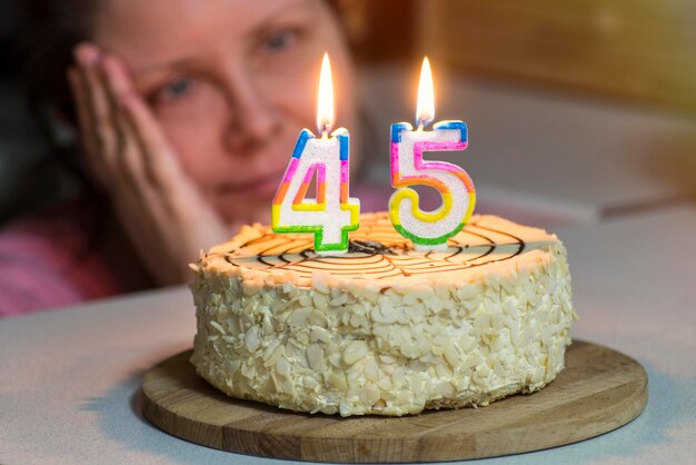 Foto close-up van een vrouw die naar verlichte cijfers op taart kijkt