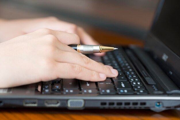 Close-up van een vrouw die op een laptop werkt met een pen