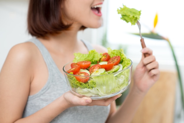 Close-up van een vrouw die verse salade eet