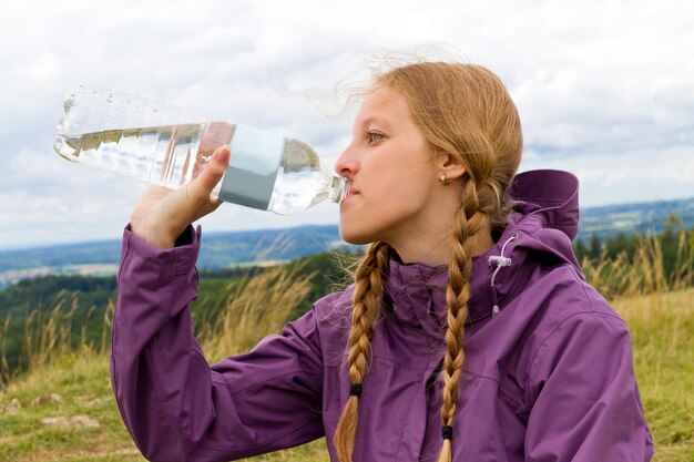 Close-up van een vrouw die water uit een fles drinkt tegen de lucht