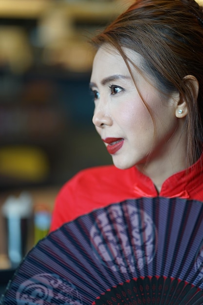 Foto close-up van een vrouw die wegkijkt terwijl ze een ventilator vasthoudt