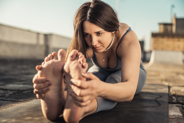 Close-up van een vrouw die yoga rekoefeningen beoefent op een dakterras. Selectieve focus.