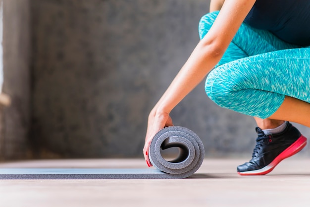 Close-up van een vrouw die yogamat vouwt