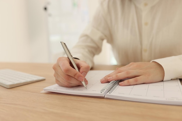 Close-up van een vrouw die zaken plant en aantekeningen maakt in de vrouwelijke manager van het kantoor die papierwerk doet