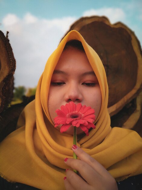 Close-up van een vrouw met een hijab die een bloem vasthoudt