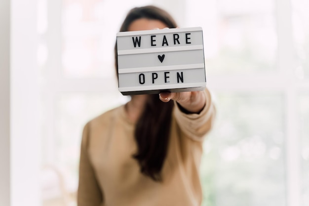 Foto close-up van een vrouw met een open bord in een winkel