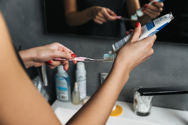 Close up van een vrouw tandpasta zetten een tandenborstel in een badkamer