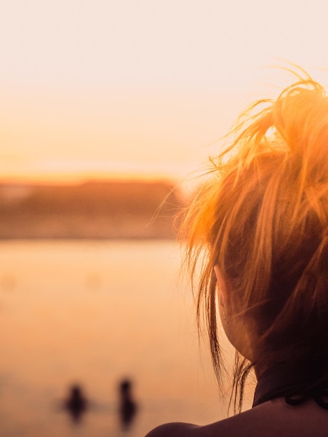 Close-up van een vrouw tegen de zee bij zonsondergang