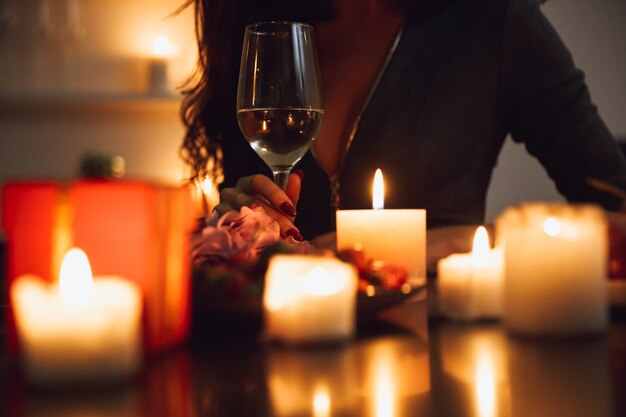 Close up van een vrouw zitten met een glas wijn aan de tafel bij kaarslicht