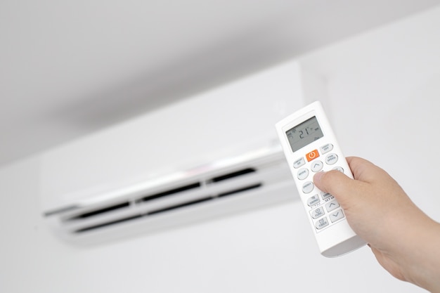 Close up van een vrouwelijke hand die een afstandsbediening van een huishoudelijke airconditioner bedient