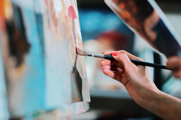 Foto close-up van een vrouwelijke hand schilderen op doek in de studio