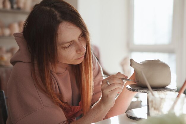 Close up van een vrouwelijke pottenbakker die een theepot maakt van klei in haar atelier