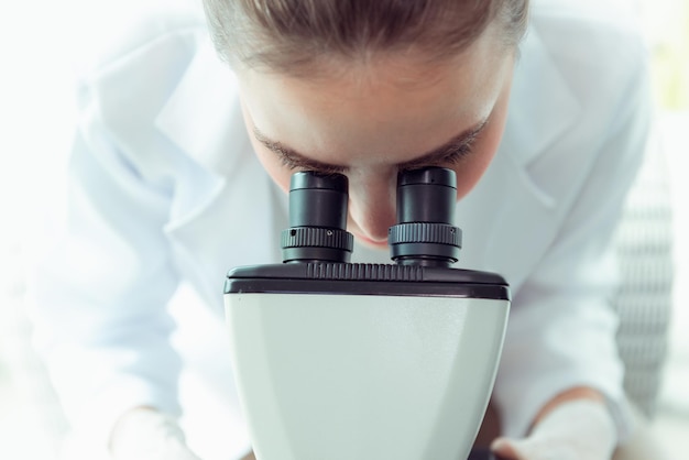 Close-up van een vrouwelijke wetenschapper die door laboratoriumapparatuur kijkt