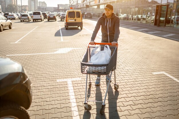 Close-up van een wandelwagen met voedsel dichtbij een grote supermarkt in een winkelcentrum in de voorsteden.