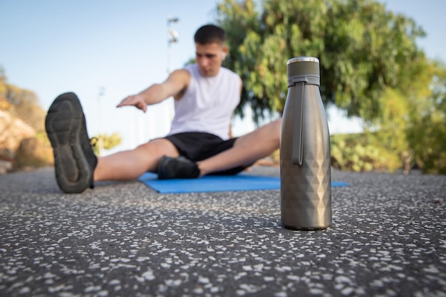 Close-up van een waterfles met atleet achter stretching, hydratatieconcept