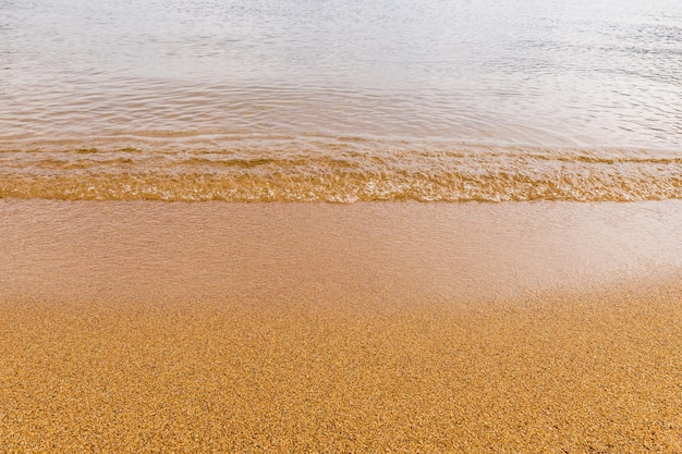 Close-up van een waterrand en geel zand zomer strand achtergrond met kopie ruimte