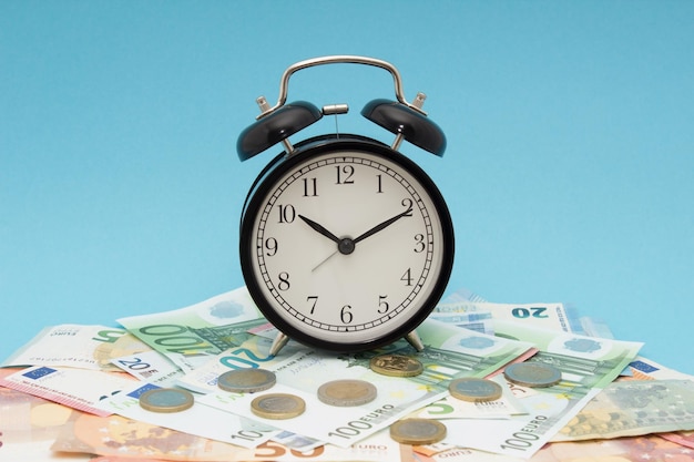 Close-up van een wekker op papiergeld tegen een blauwe achtergrond