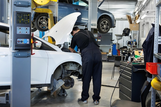Close-up van een werknemer een reparateur die een auto repareert de open kap van de auto in de reparatie garage