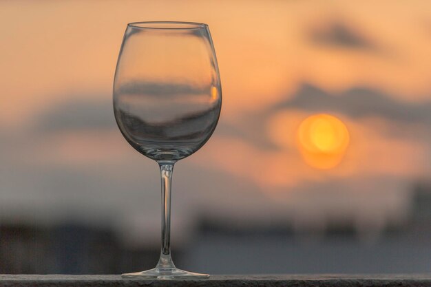 Close-up van een wijnglas op tafel tegen zonsondergang