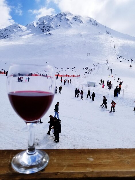 Foto close-up van een wijnglas tegen een besneeuwde berg