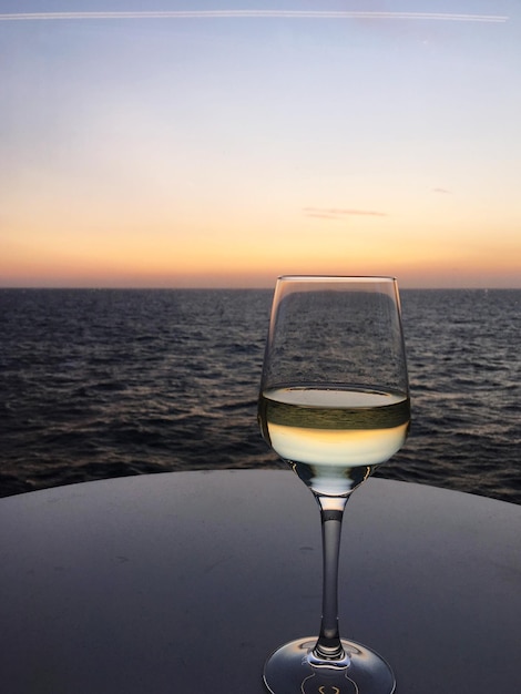 Close-up van een wijnglas tegen een heldere hemel bij zonsondergang