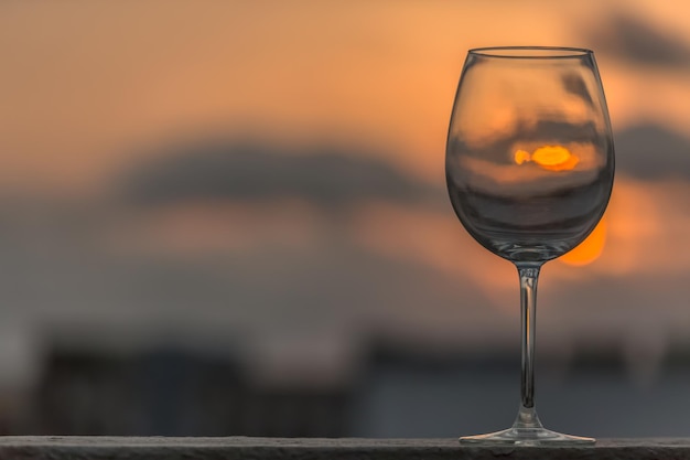Close-up van een wijnglas tegen een oranje hemel