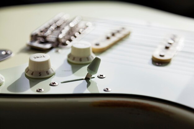 Foto close-up van een witte elektrische gitaar met snaren en knoppen