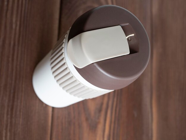 close-up van een witte en bruine thermische beker voor dranken op een houten achtergrond